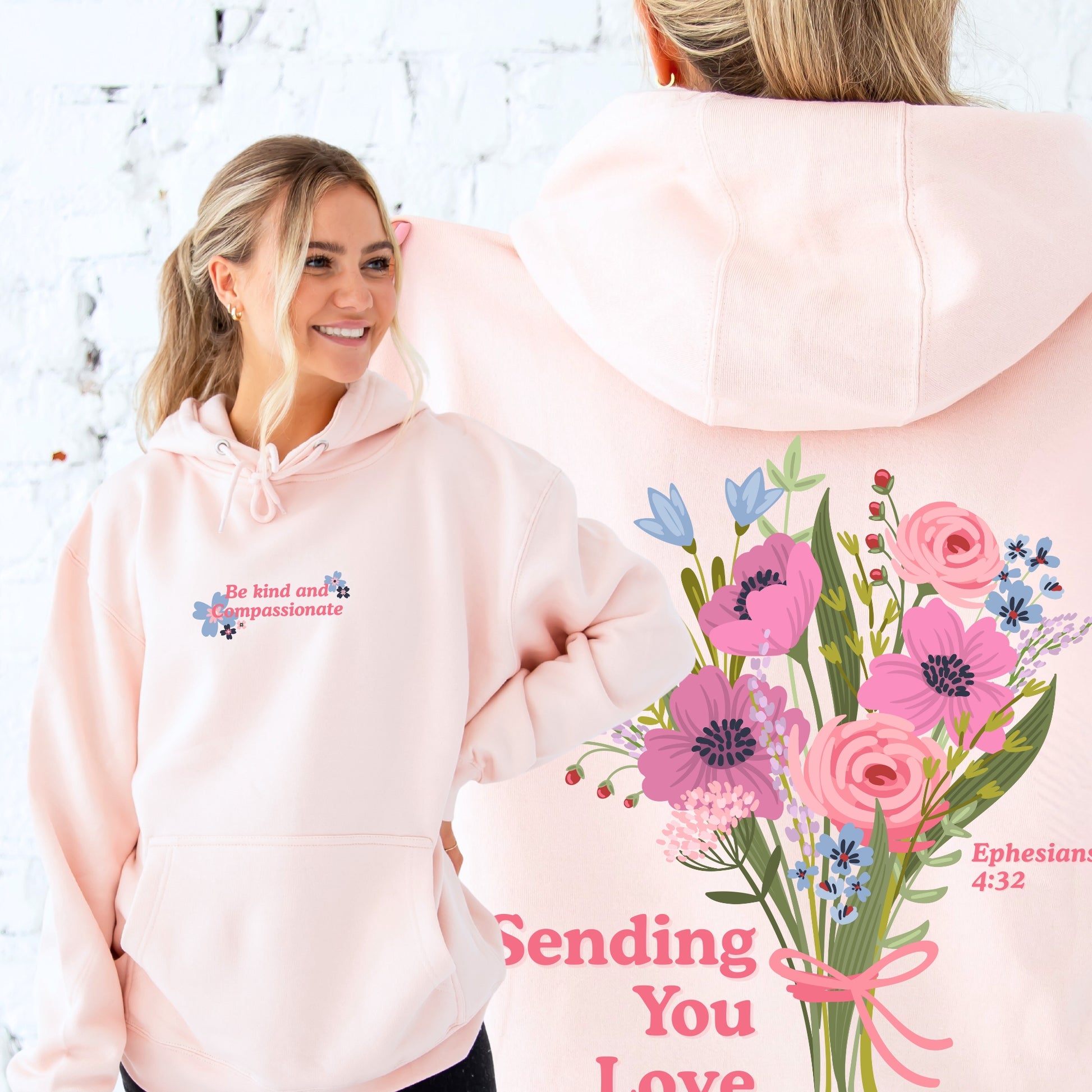 A woman wearing pink hoodies with floral designs and text.