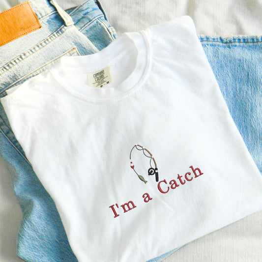 white comfort colors t-shirt with fishing rod icon and custom text embroidered on the center chest