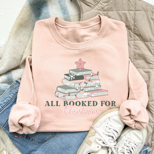 blush pink crewneck sweatshirt with a cute all booked for Christmas design featuring books stacked up to resemble a Christmas tree in shades of soft pink and greens