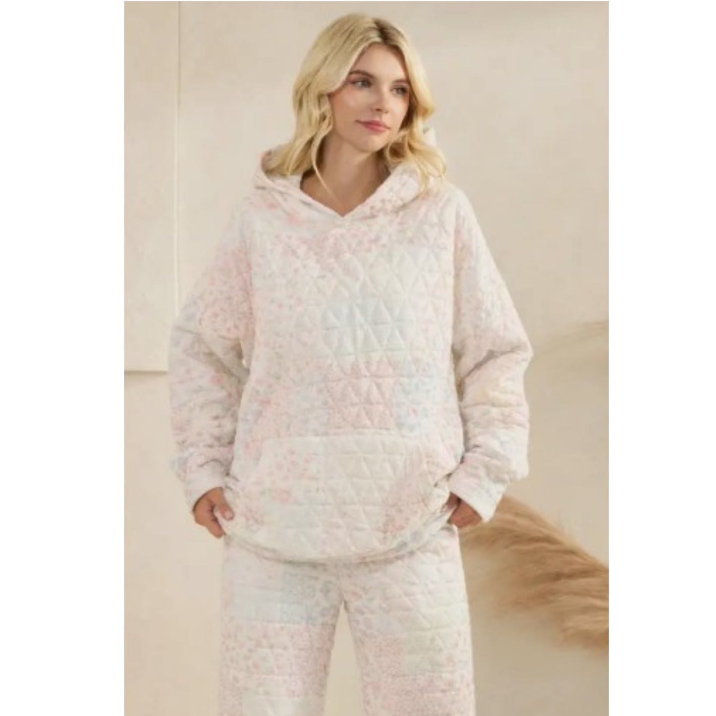 Woman wearing a light-colored quilted hoodie and pants set against a neutral background