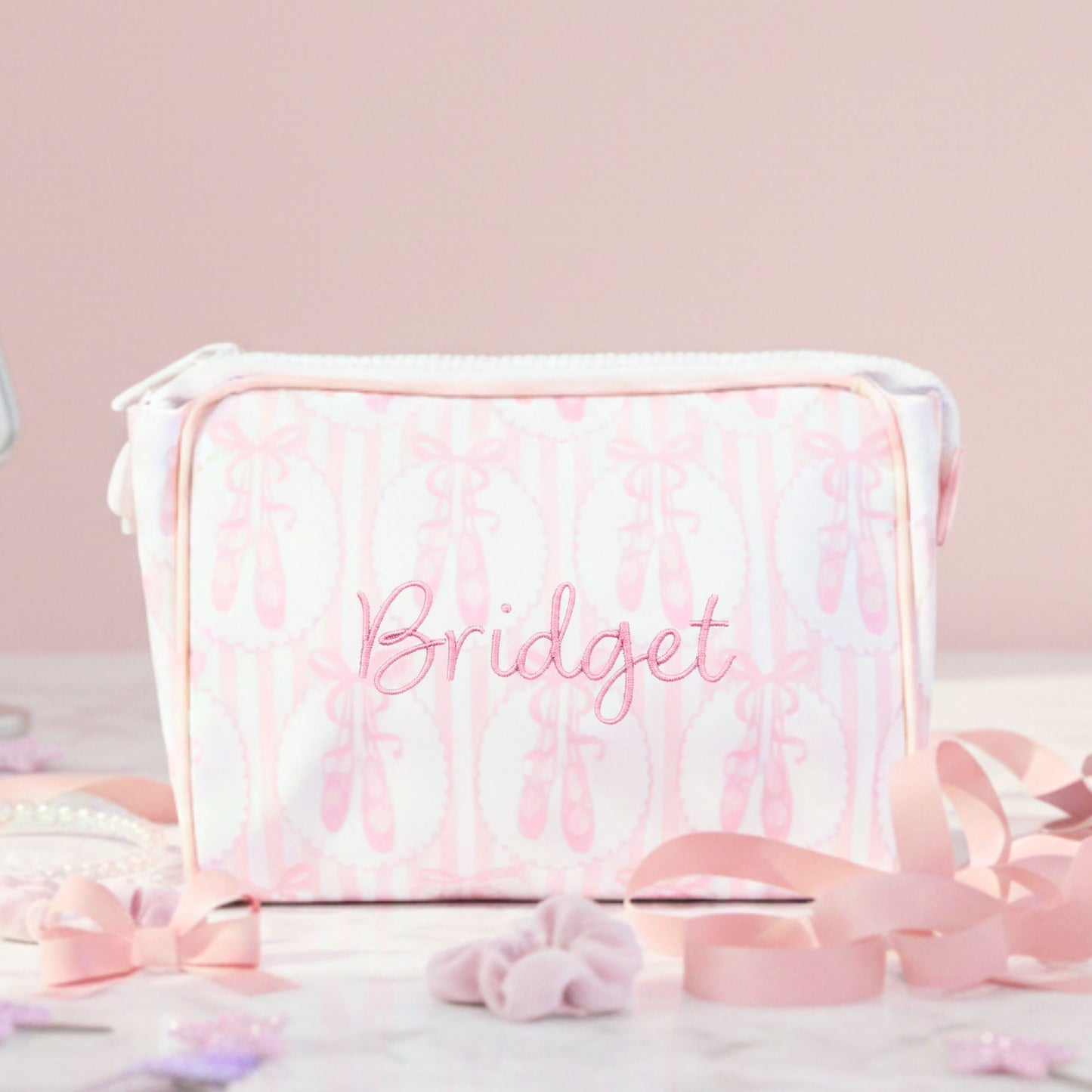 Pink and white ballet slipper striped pattern pouch with 'Bridget' embroidered on it, surrounded by decorative ribbons.