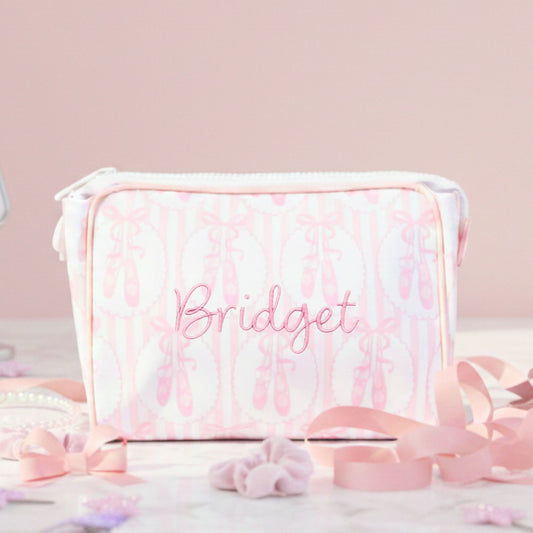 Pink and white ballet slipper striped pattern pouch with 'Bridget' embroidered on it, surrounded by decorative ribbons.