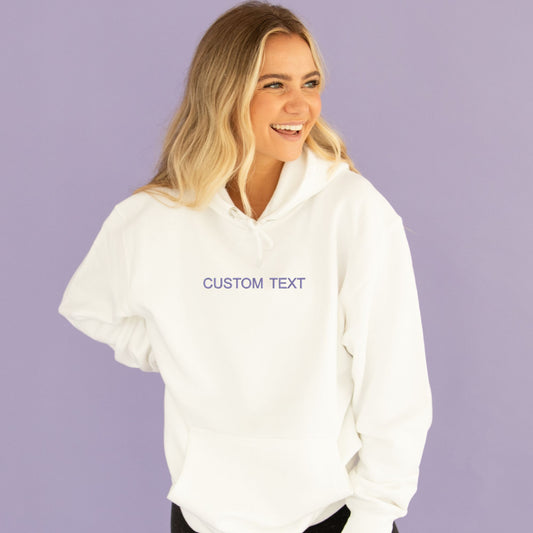 young woman wearing a white hoodie with custom embroidered text in purple thread