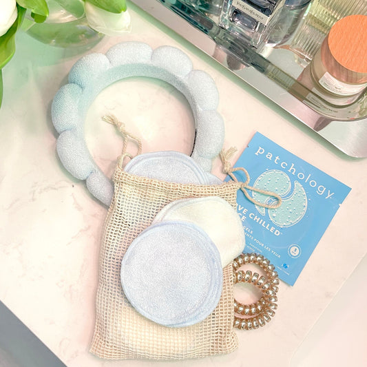 bathroom counter with a spa headband, reusable cotton rounds, patchology eyepatches, and coiled hair tie 