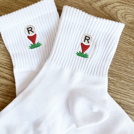 white crew socks with custom golf ball and tee embroidered icon with single letter monogram embroidered on top of the golf ball.