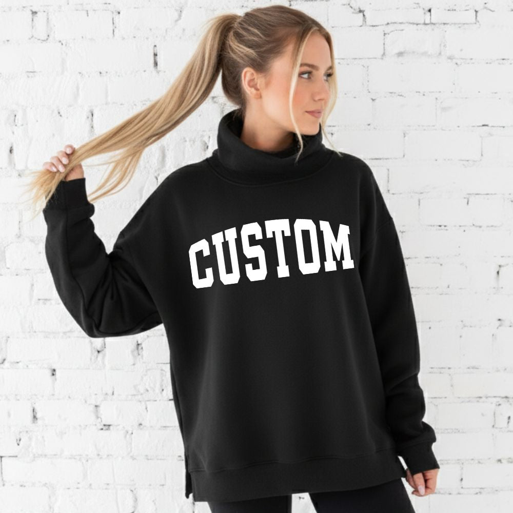 Person wearing a black sweatshirt with 'CUSTOM' printed on it against a white brick wall.