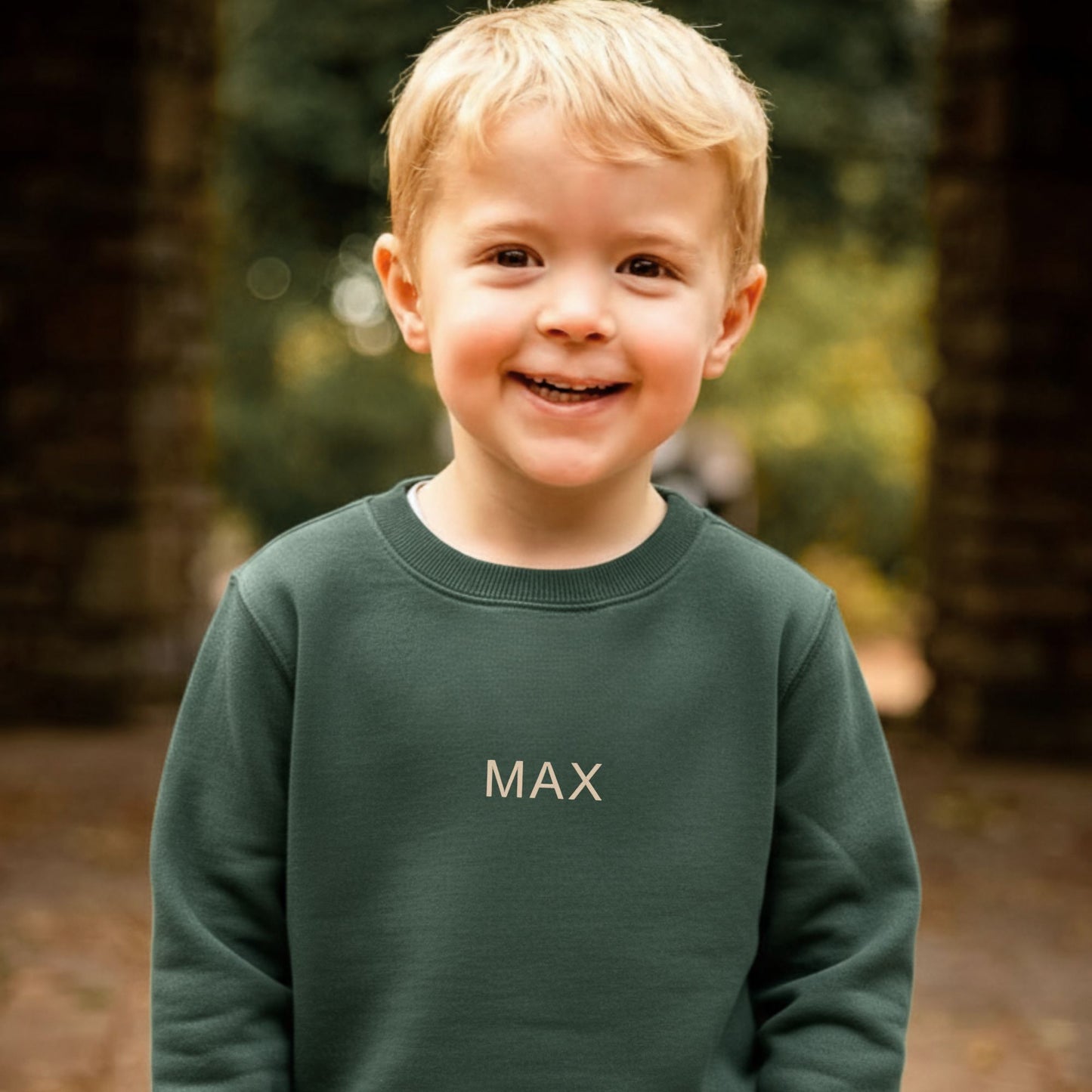 Child wearing a green sweatshirt with 'MAX' on it, standing outdoors.