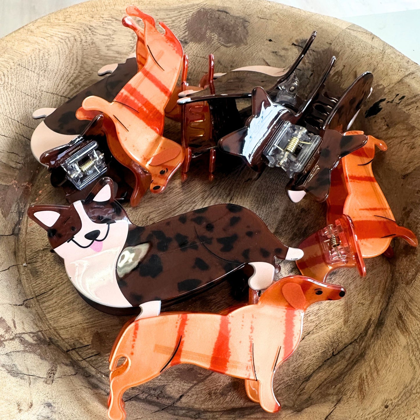 Collection of dog-shaped hair clips in a wooden bowl