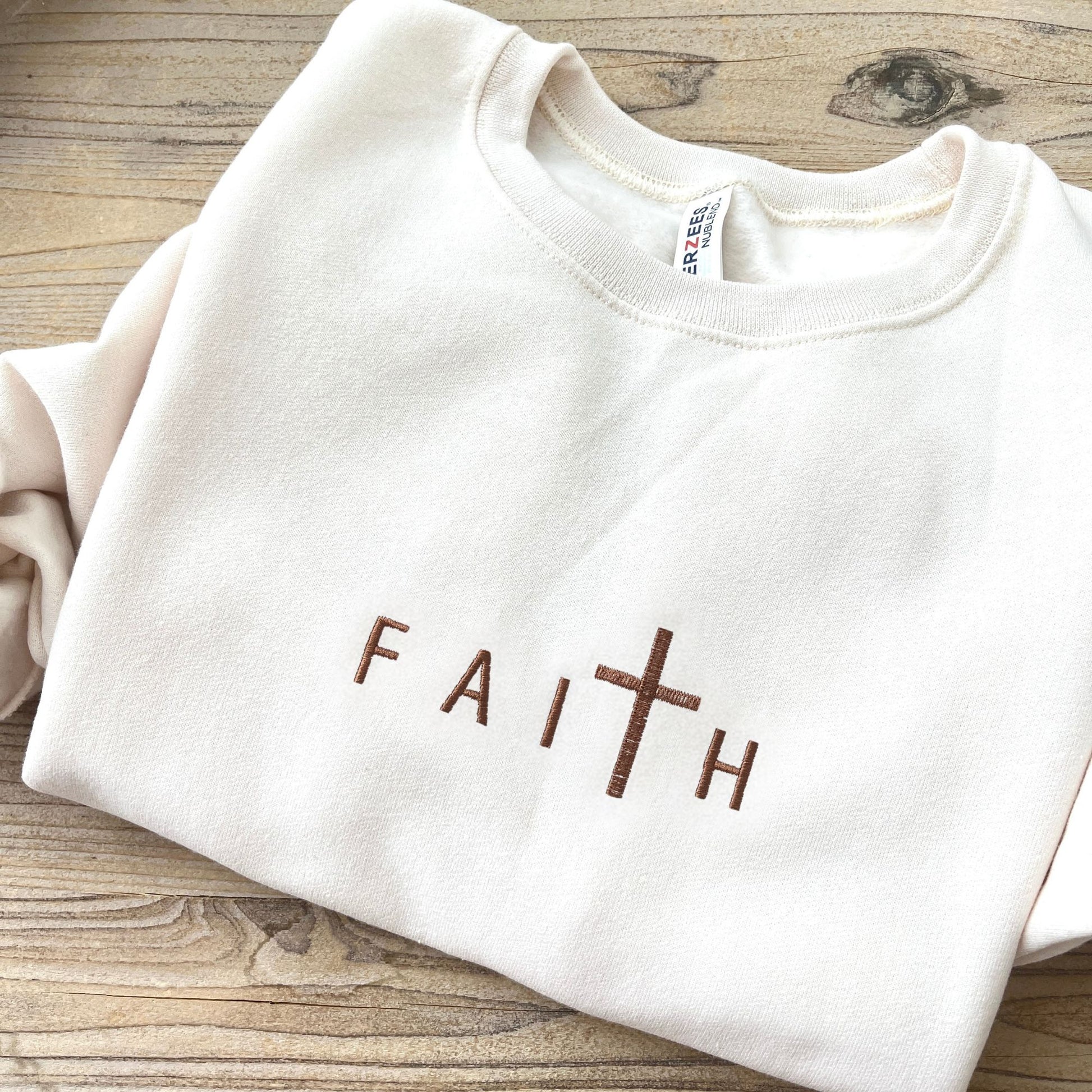 sweet cream crewneck with custom embroidered design of FAITH with a cross for the T in chestnut thread.