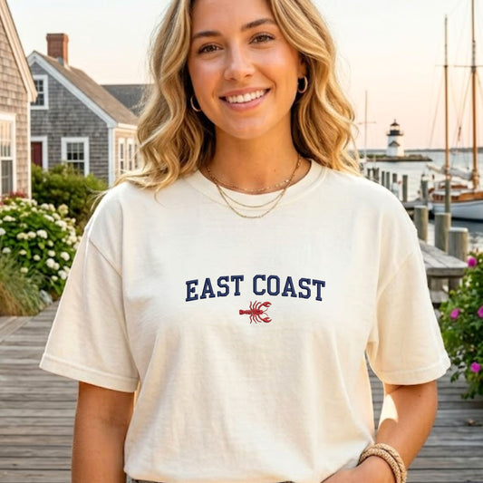Woman wearing a 'East Coast' t-shirt with a lobster graphic on a dock background