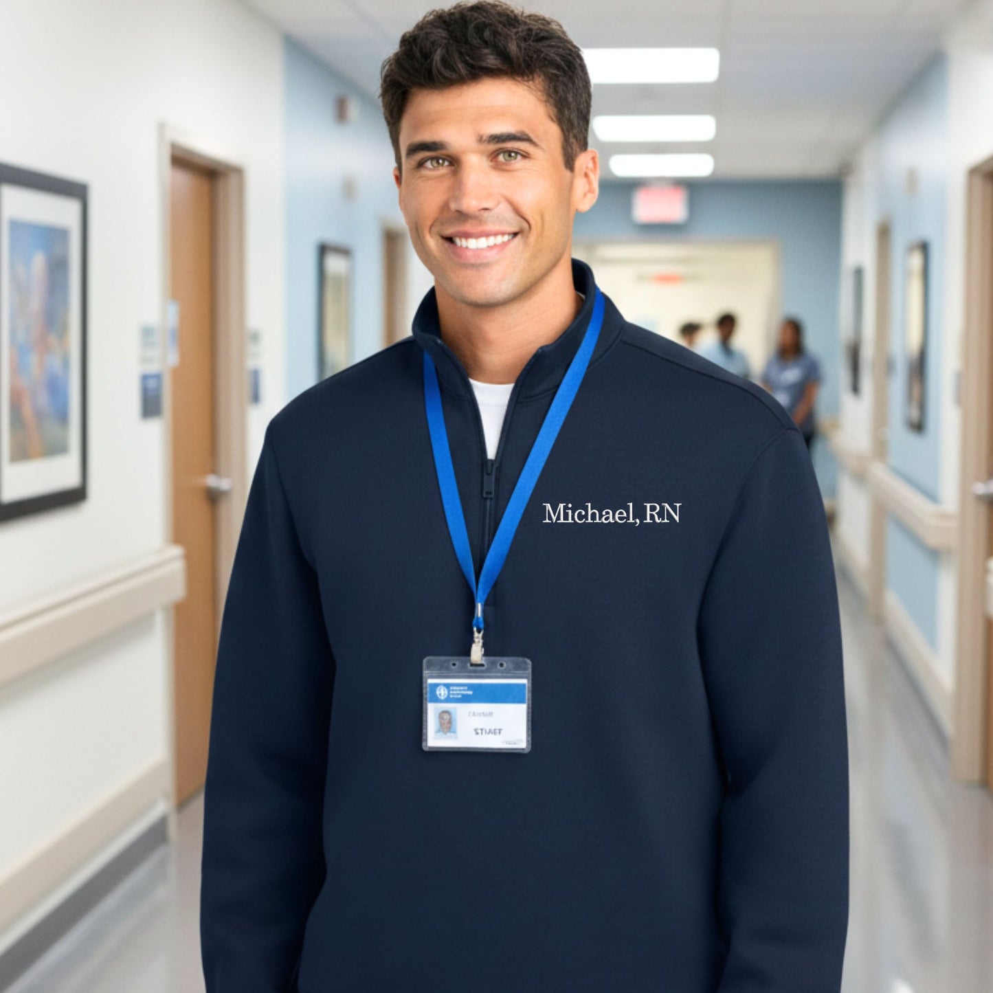 Man wearing a navy blue sweatshirt with 'Michael, RN' on it in a hospital hallway.