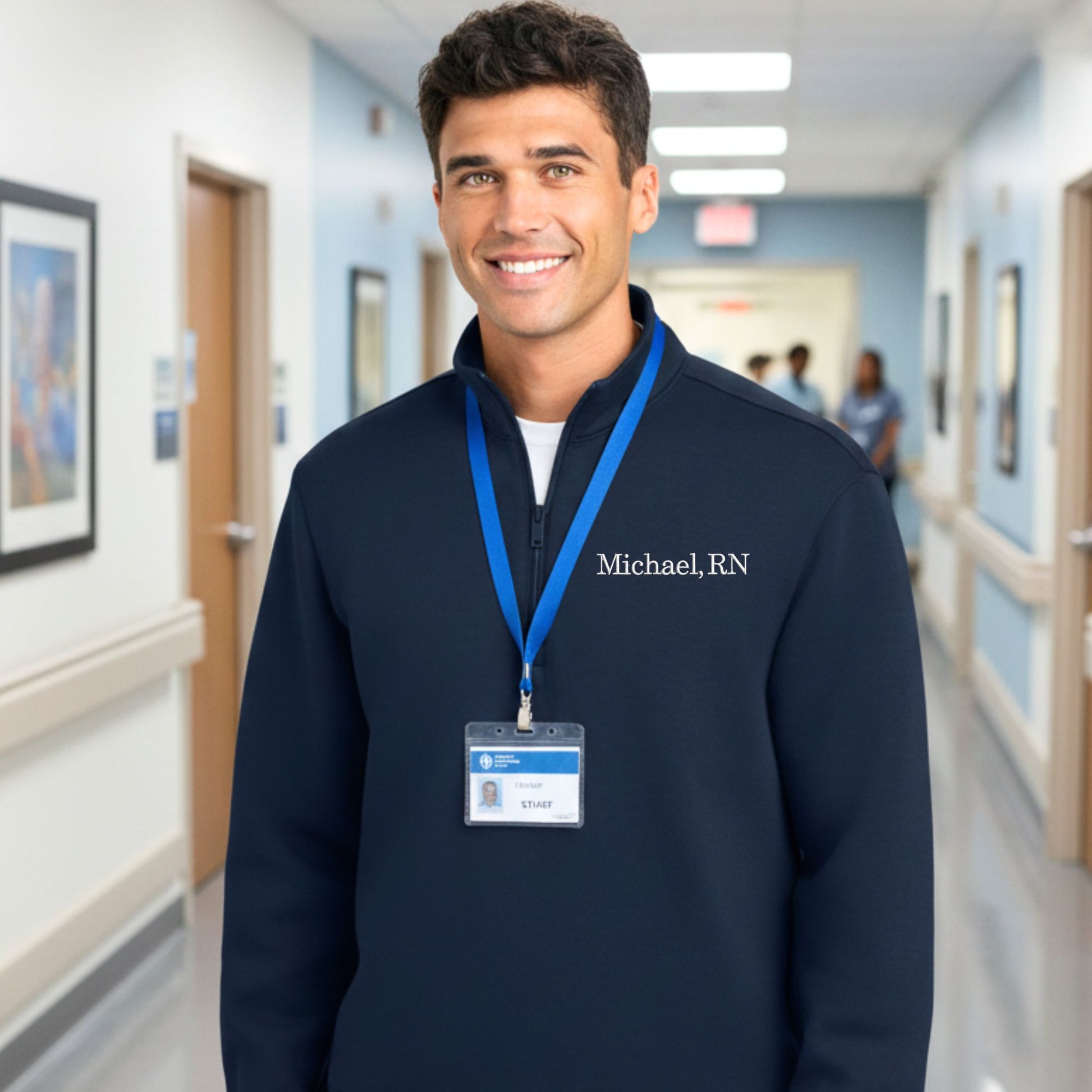 Man wearing a navy blue sweatshirt with 'Michael, RN' on it in a hospital hallway.