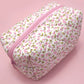 Floral-patterned pouch with a pink zipper on a pink background