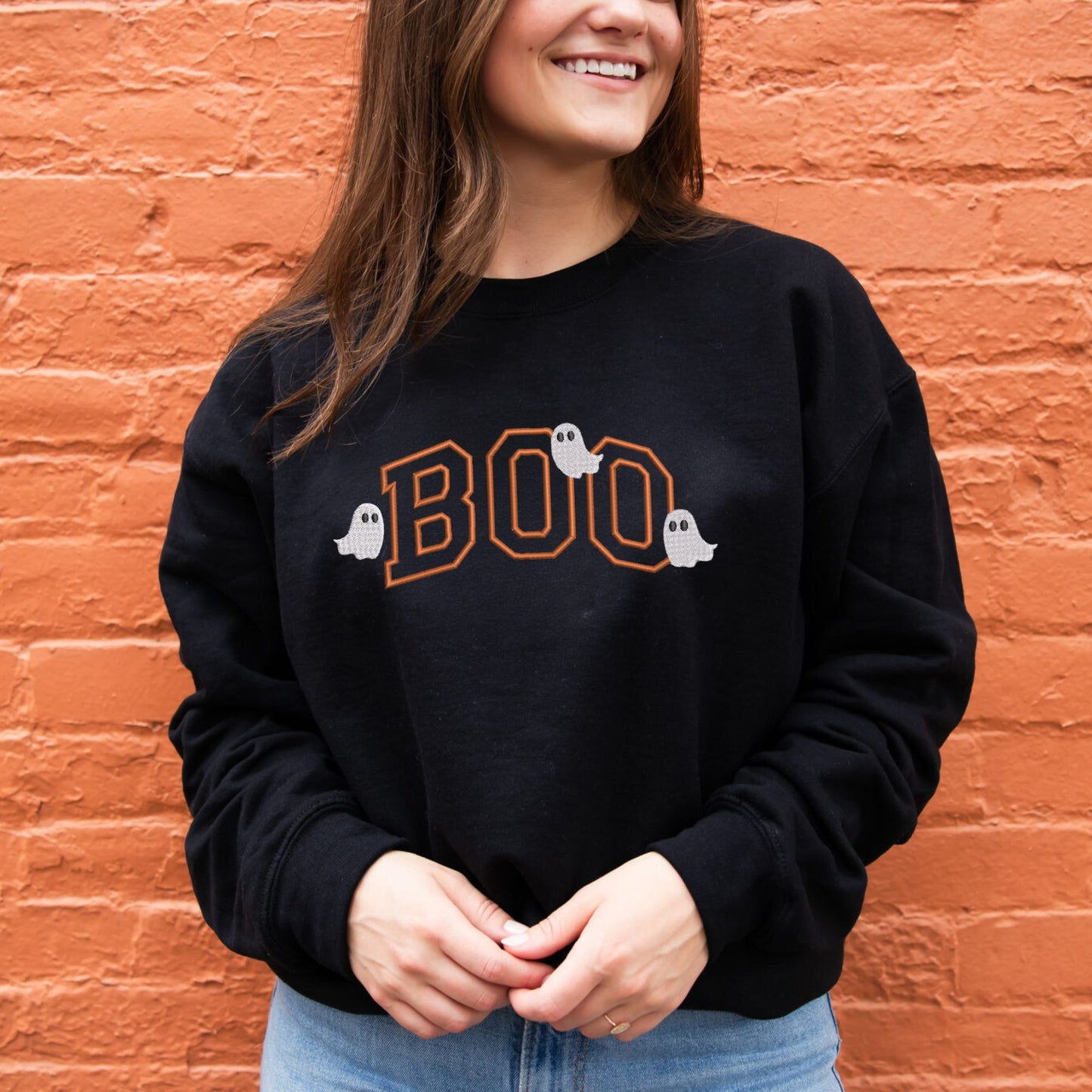 young woman wearing a black crewneck with embroidered Boo Pumpkin Spice thread and little ghost over the design