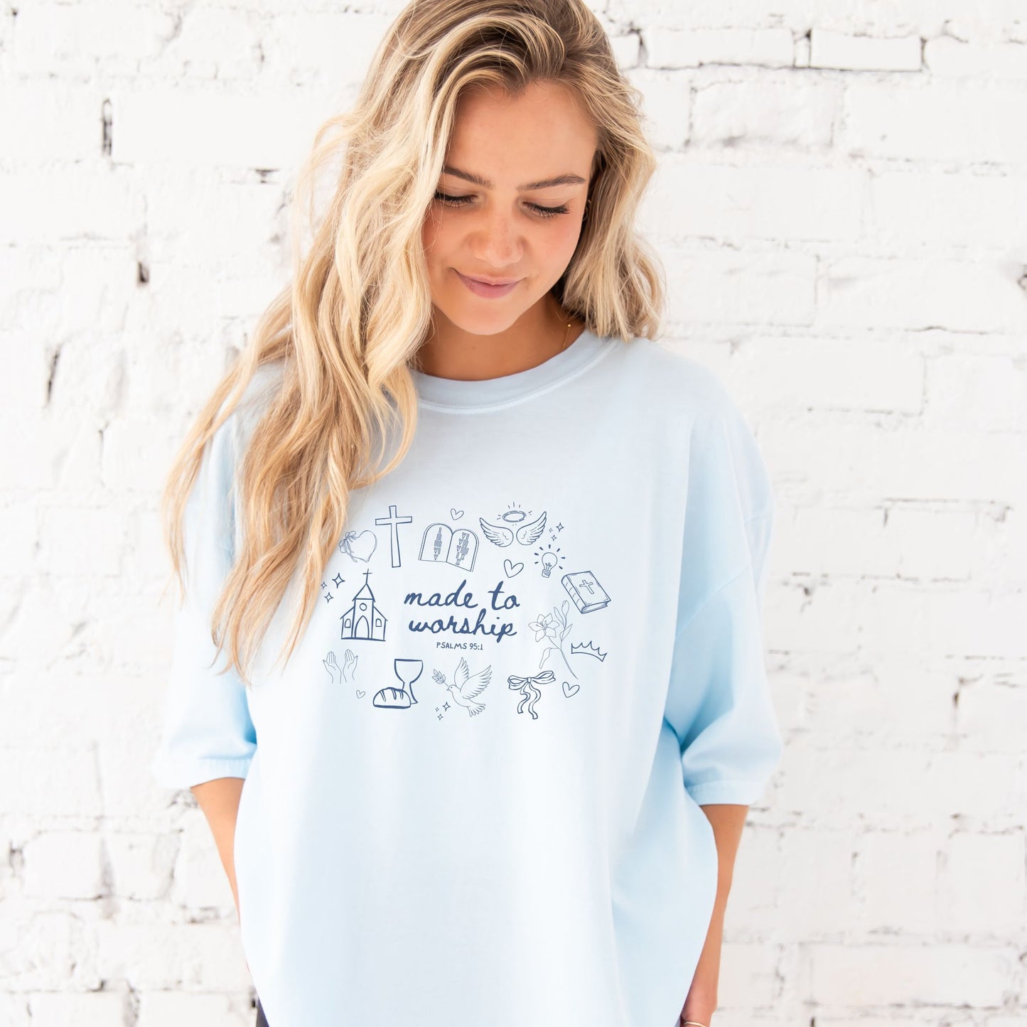 girl wearing a chambray comfort colors t-shirt with custom made to worship printed design featuring cute Christian themed drawn icons