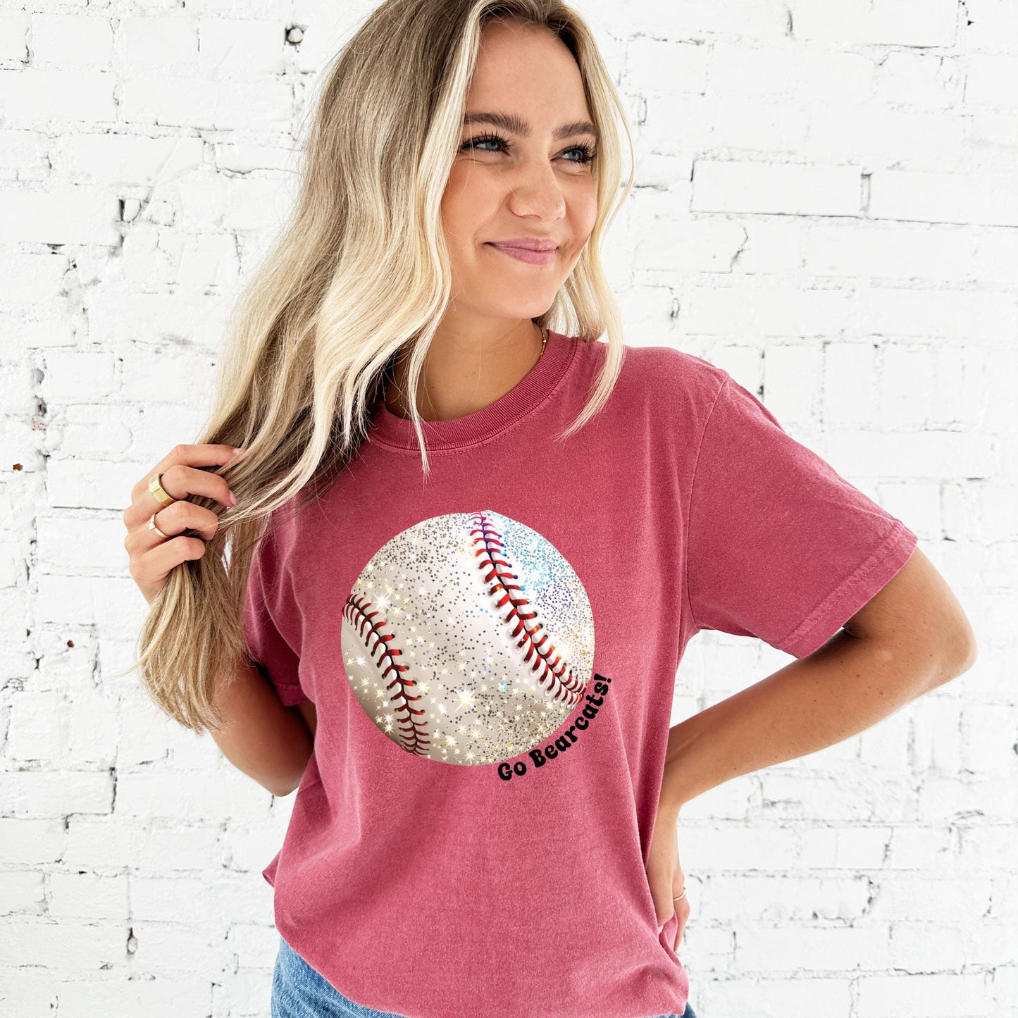 young woman wearing a crimson comfort colors t-shirt with large glitter baseball print and Go Bearcats text curved around the design in black ink