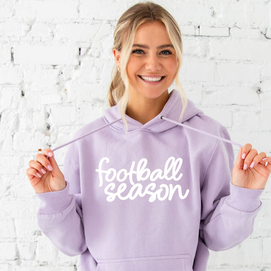 girl wearing lilac hooded sweatshirt with football season cursive white print