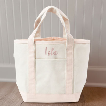 Canvas  tote bag with pink trim and 'Isla' embroidery on a wooden floor.