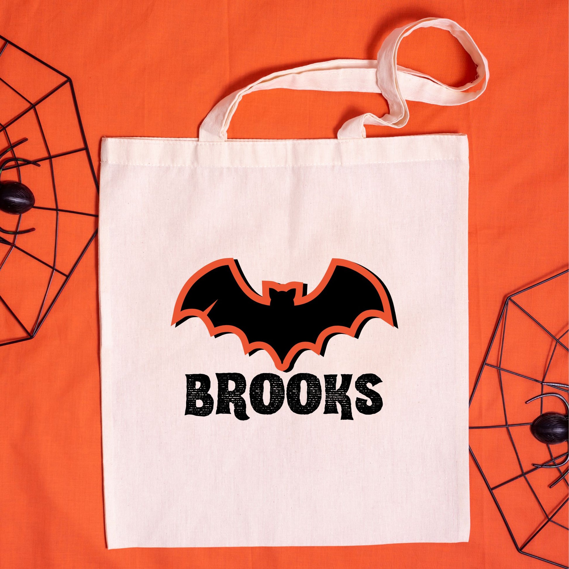 natural canvas tote bag with a custom name and bat print, bat featuring an orange outline