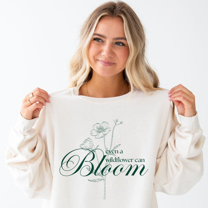 girl wearing an oversized sweet cream crewneck sweatshirt with a cute even a wildflower can bloom printed floral design