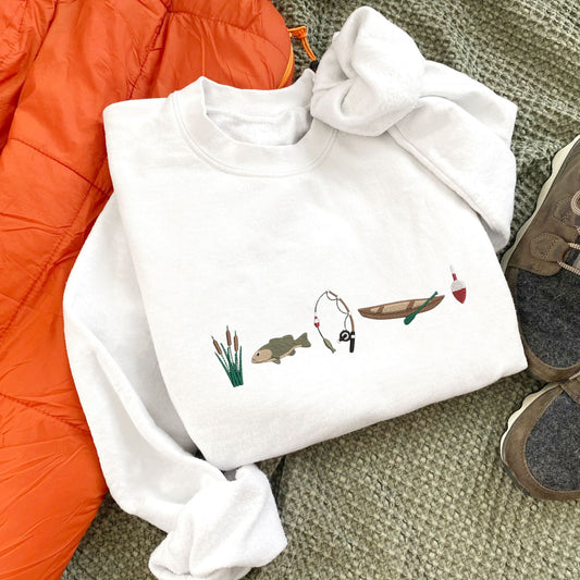 white crewneck with custom embroidered fishing icons including cattails, bass fish, fishing rod, canoe, and bobbin across the chest