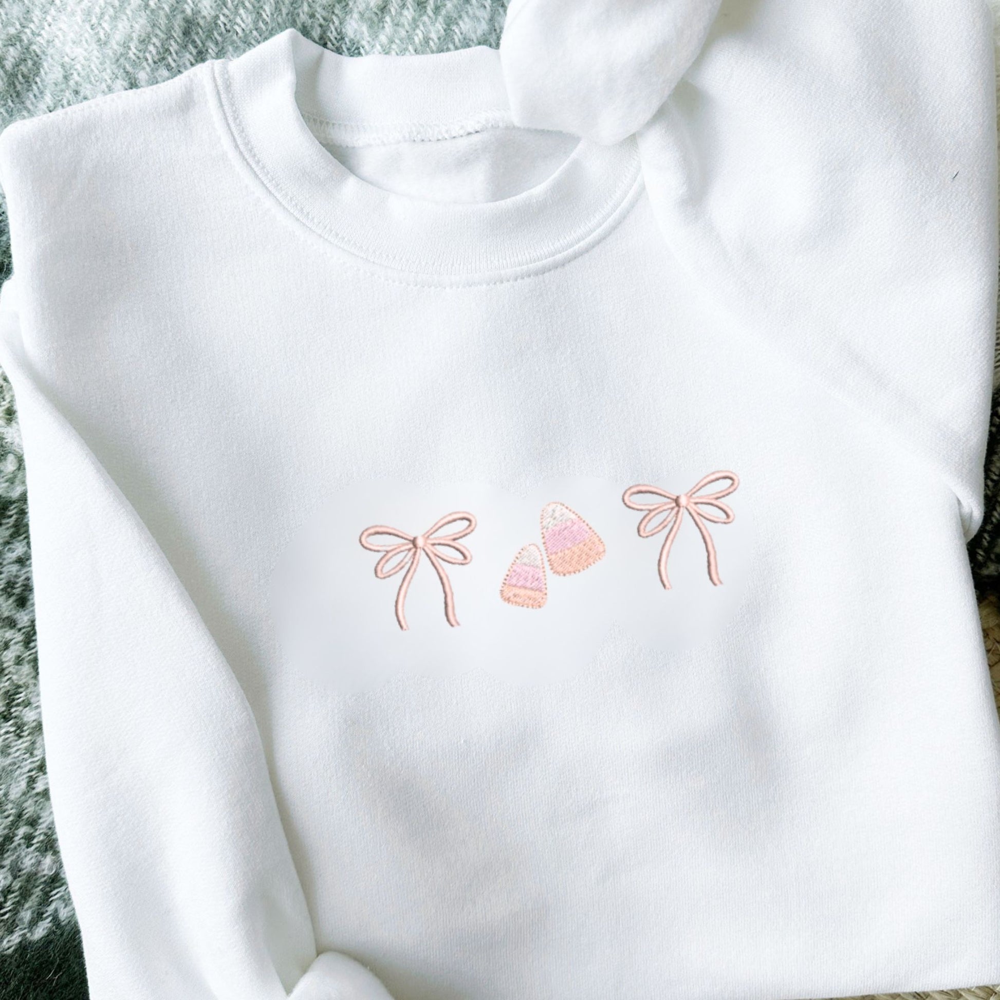 White sweatshirt with embroidered double loop mini bow and candy corn design 