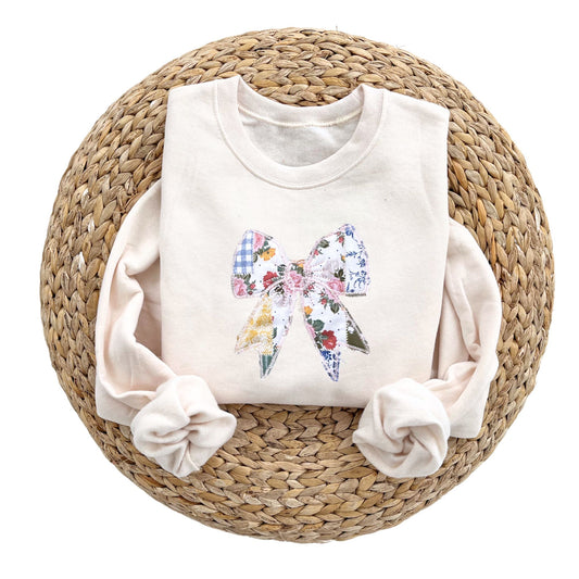 a sweet cream crewneck sweatshirt with a custom embroidered bow with vintage inspired patchwork quilted colorful printed fabric