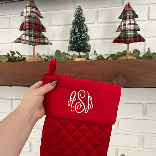 close up of a red quilted stocking with embroidered monogram in white thread.