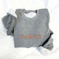 Gray sweatshirt with orange graphics on a white background