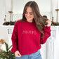 young woman modeling a cardinal red crewneck sweatshirt with christmas outlined icons embroidered across the chest in white thread.