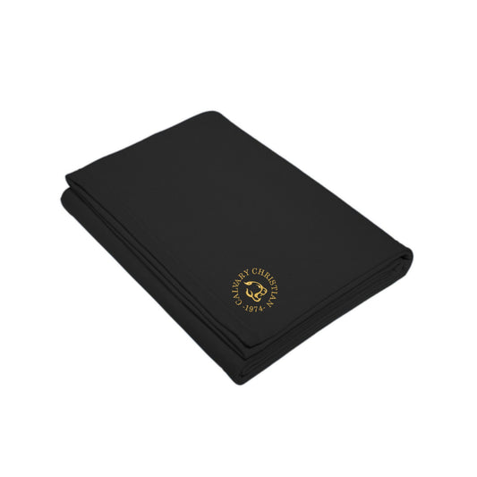 folded black sweatshirt blanket with a round calvary christian 1975 cougar logo embroidered in gold thread on the corner
