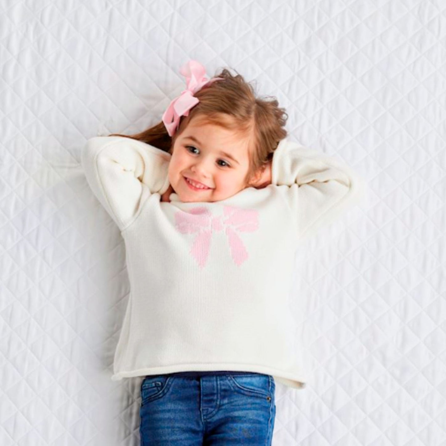little girl wearing a pink bow rollneck white sweater