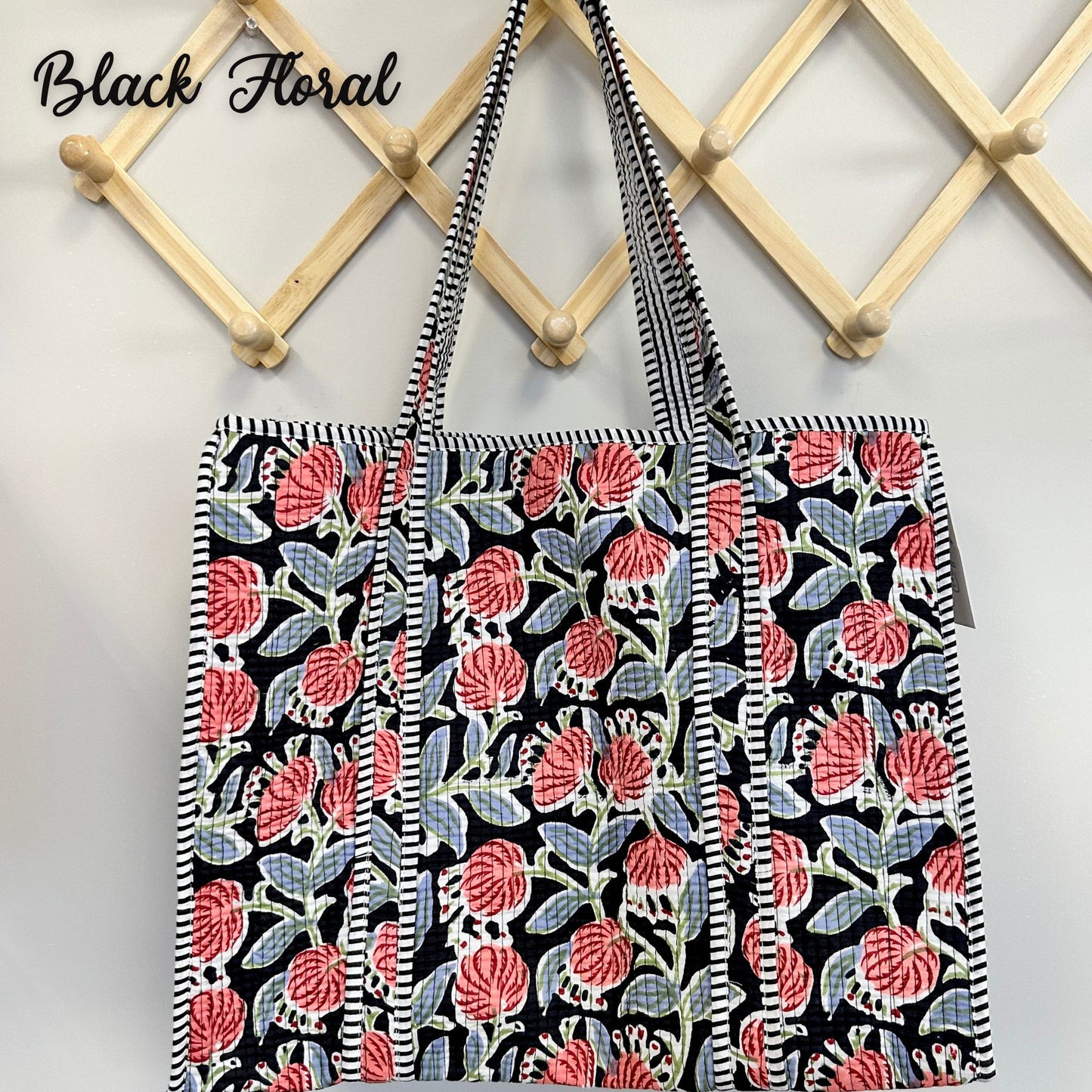 Floral patterned bag hanging on a wooden rack with 'Black Floral' text.