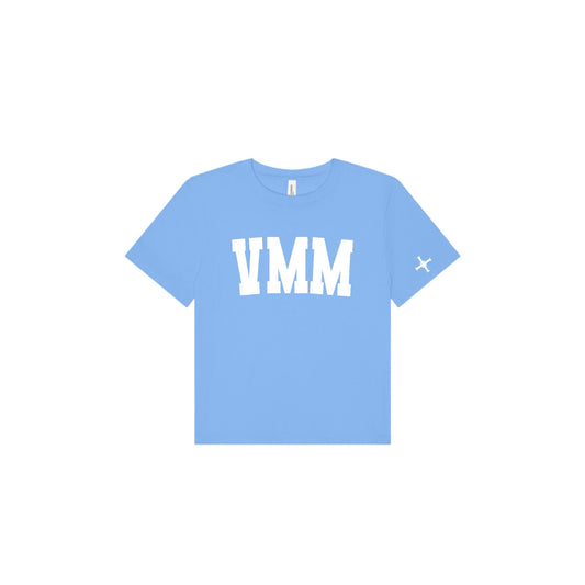 A light blue short-sleeve t-shirt with 'VMM' printed in bold white block letters across the chest and a small white 'cross' logo on the left sleeve, shown on a plain white background.