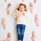 Child surrounded by dolls on a textured white surface
