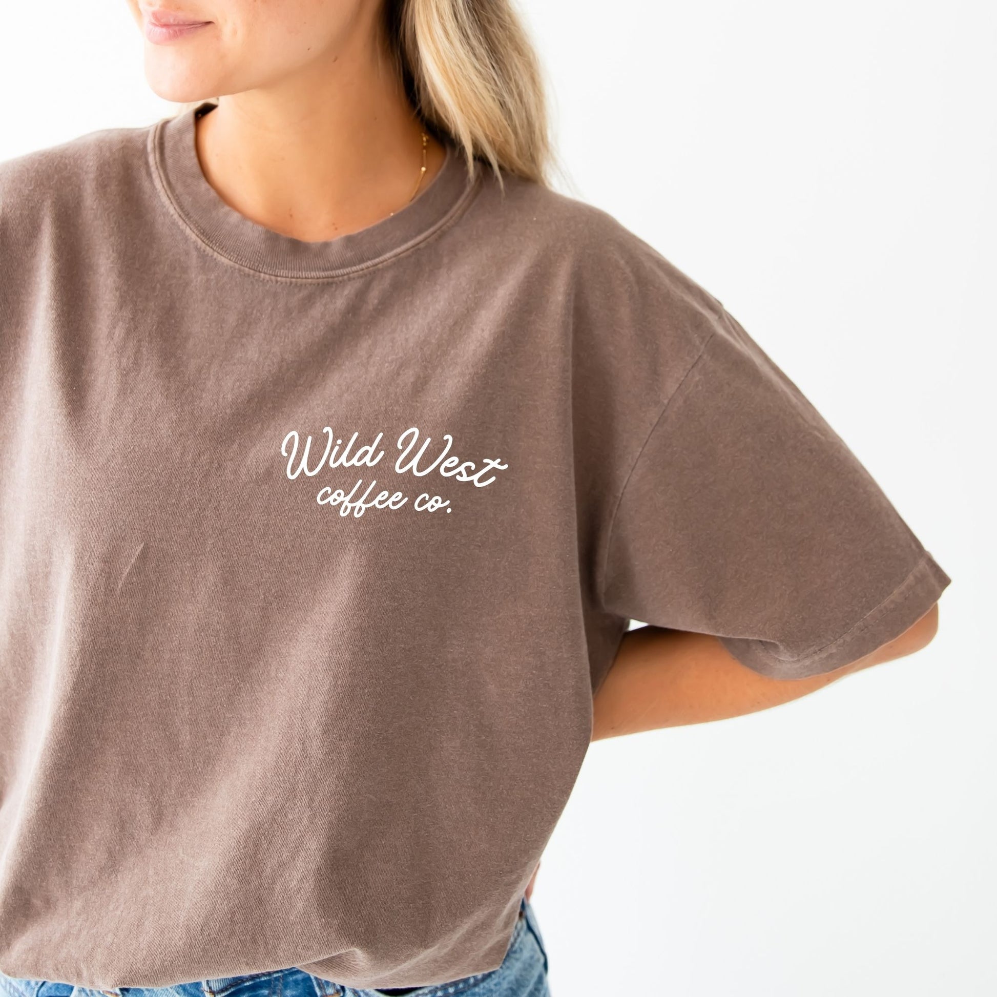 a woman wearing an espresso brown comfort colors t-shirt with custom wild west coffee co. printed design on the front left chest 