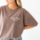 a woman wearing an espresso brown comfort colors t-shirt with custom wild west coffee co. printed design on the front left chest 
