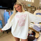 Woman wearing a white sweatshirt with 'Pilates is my happy hour' text in a store setting.