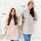 side by side of a two women wearing a pullover hooded cozy blanket. the woman on the left is 5'2" and the woman on the right is 5'11", showing how it will fit on different heights