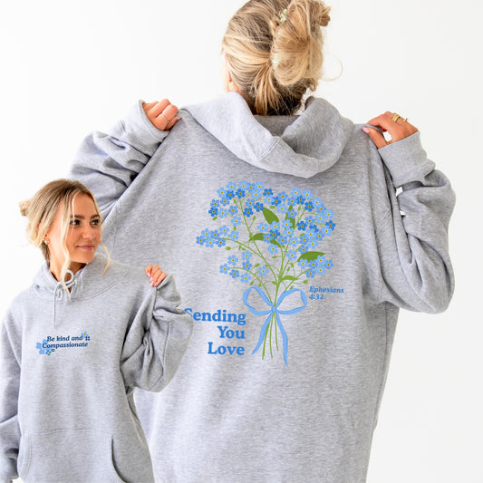 a girl wearing a gray hoodie with a floral design and text on the back.