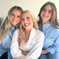 Three women wearing embroidered shirts posing together.