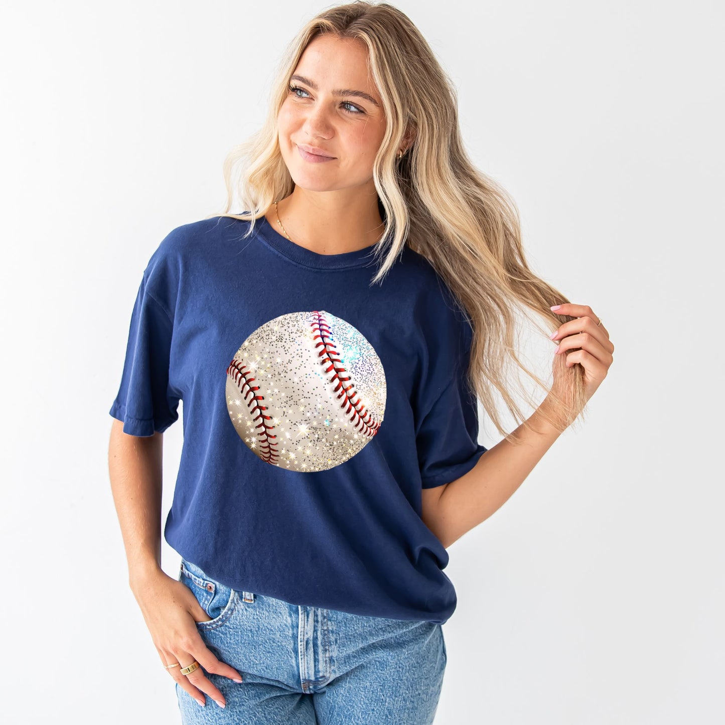 young woman wearing a navy comfort colors t-shirt with large glitter baseball print n the chest