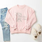 Pink sweatshirt with 'Olive You' design, light blue jeans, and beige sneakers on a white background