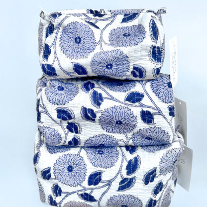 Stack of quilted pouches with blue floral pattern on a light blue background
