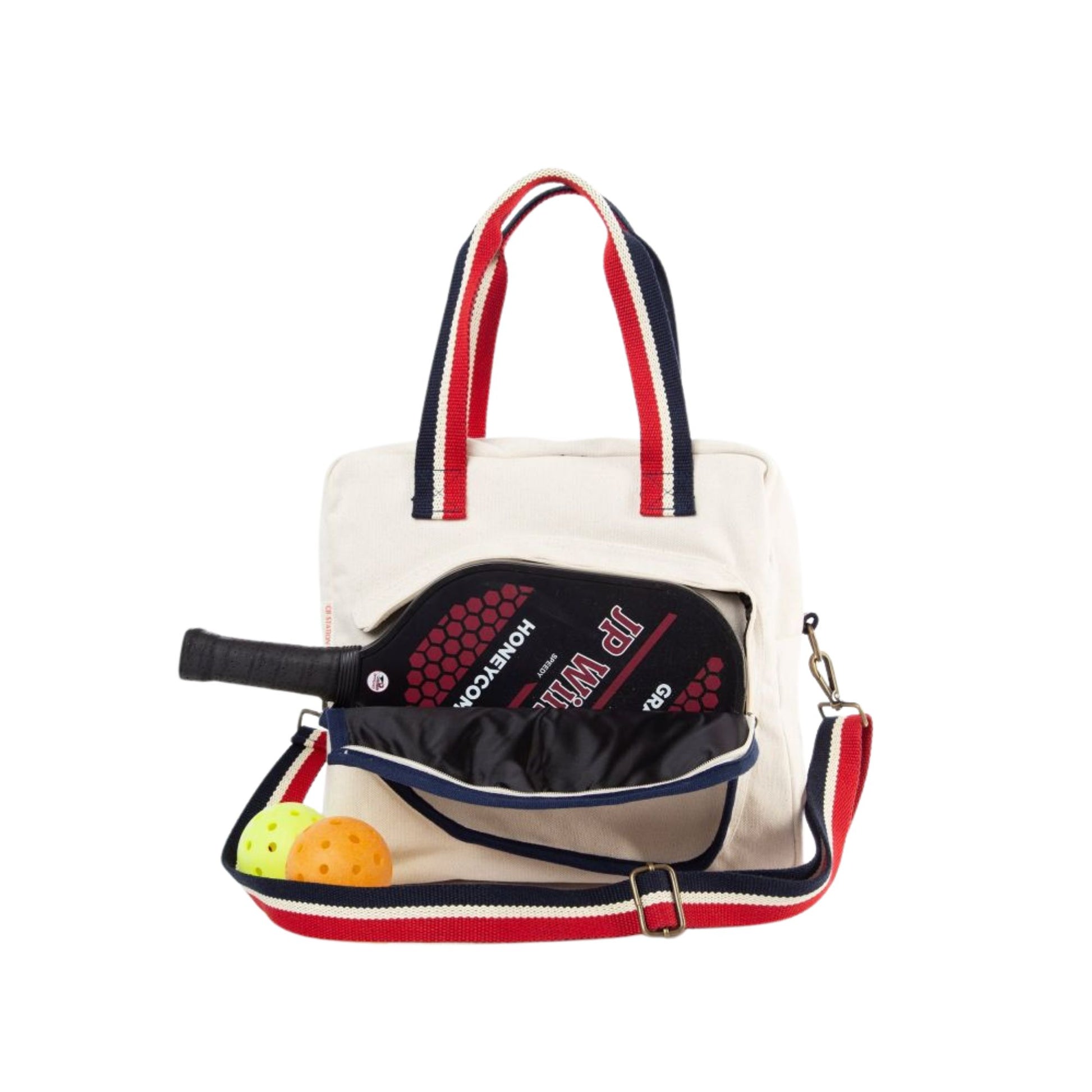 natural canvas pickleball bag with red and navy striped handle and crossbody strap, with the pocket unzipped showing how the paddle slides in