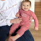 baby wearing a mauve fleece romper with embroidered little sister in white thread on the chest