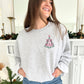 young woman wearing an ash crewneck with custom very merry and outlined tree embroidered design