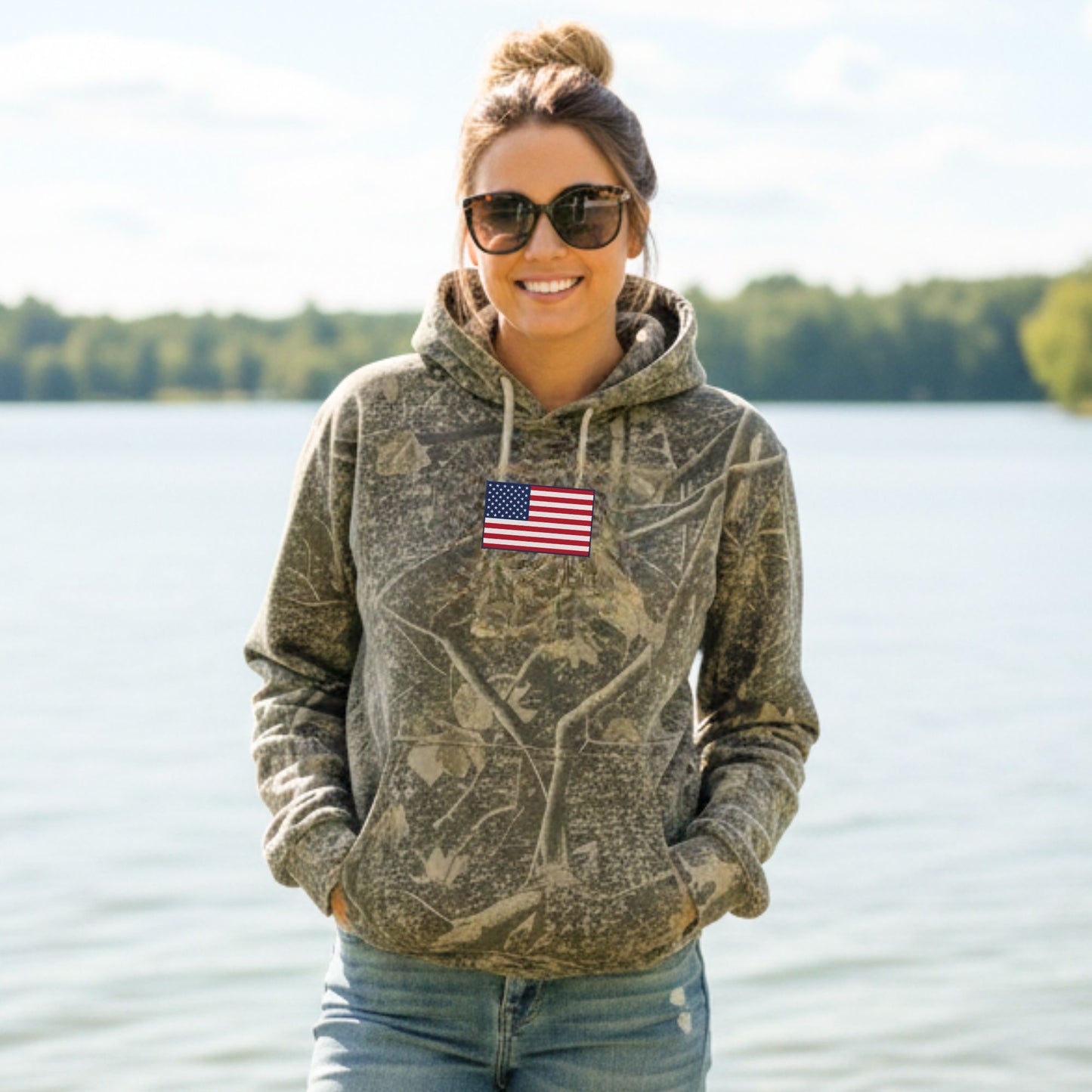 Woman wearing a camouflage hoodie with an American flag patch by a lake