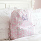 Pink and white bow patterned backpack with 'kah' text on a bed