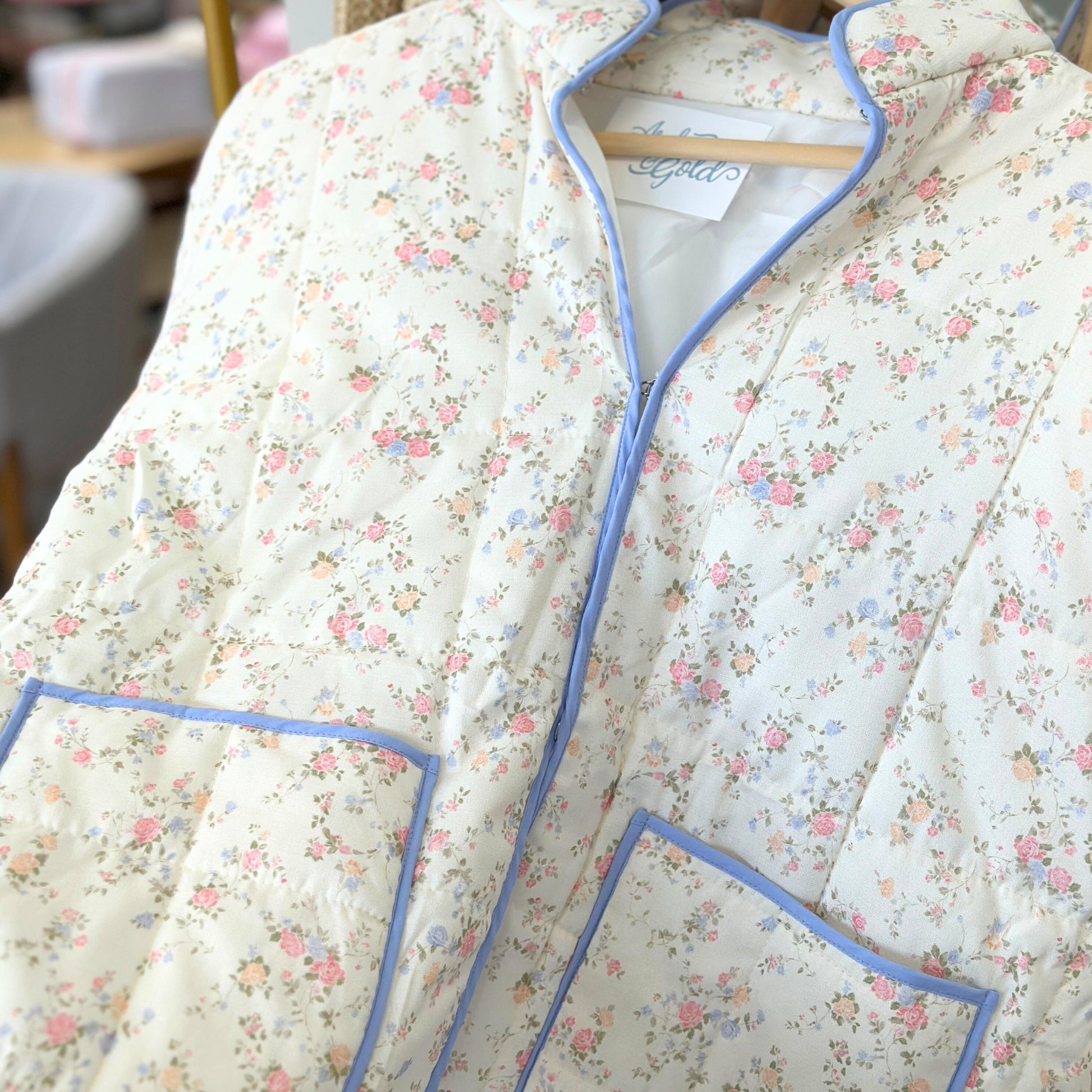 Floral quilted jacket with blue piping on a hanger